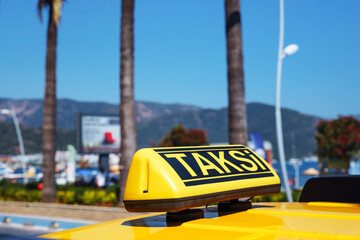 Closeup. Yellow taxi sign on the roof of a car under a blue sky