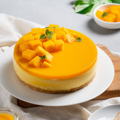 Delicious glazed mango no baked cheese cake with fresh diced mango pulp topping on bright table...