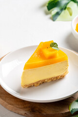 Delicious glazed mango no baked cheese cake with fresh diced mango pulp topping on bright table background.