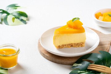 Delicious glazed mango no baked cheese cake with fresh diced mango pulp topping on bright table background.