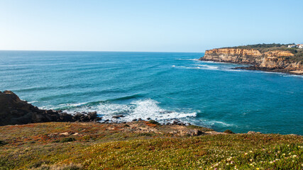 Scenic ocean  landscape on summer sunny day.  Beautiful  rocky coast with blue sky. Portugal. Europe. Beautiful natural landscape with ocean rocky shore with green grass on the foreground.