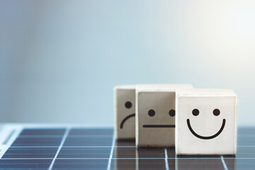 Smile face in bright side and sad face in dark side in wooden block cube on photovoltaic solar...