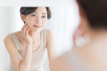 Obraz na płótnie Canvas 朝、鏡を見ながらスキンケアスキンケアをするアジア人女性