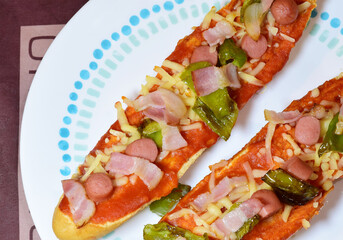 Zenith view, pizza bread, with mozzarella, tomato sauce, frankfurt, beacon and strips of green pepper.