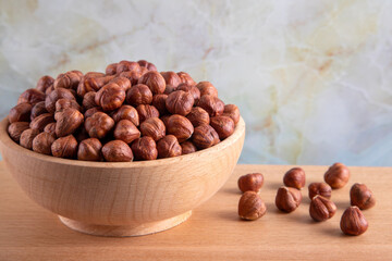 Bowl full of hazelnuts on wooden background
