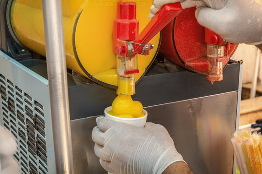 Seller pours frozen juice or serbet into a once-only glass from the machine. Close-up