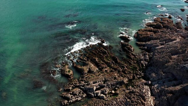 Aerial view of the ocean crashing into the rocks on the coast of swansea, mumbles UK. clear blue coast stunning views.