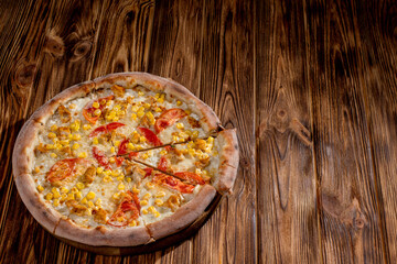 Pizza for children on a cream base with chicken fillet, tomatoes, corn and mozzarella cheese on wood background. Copy space.