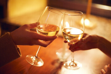 Evening in a cafe. Two girls clink glasses against the background of a burning candle.