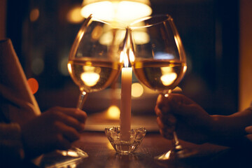 Evening in a cafe. Two girls clink glasses against the background of a burning candle.
