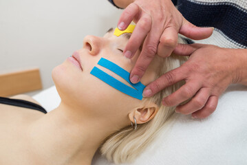 female cosmetician doing the taping of the face of the patient