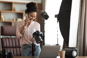 Beautiful creative woman photographer working, having phone conversation, holding camera - obrazy, fototapety, plakaty