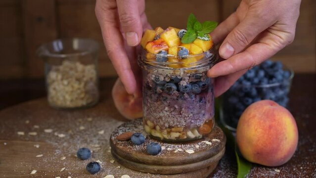 Granola parfait with berries and yogurt . Parfait with granola, teaspoon , raspberries and blueberries on a black background . Granola in a glass .