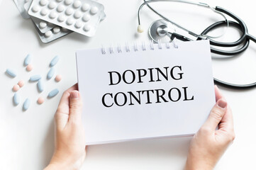 Doctor holding clipboard with text Doping Control on white background, closeup