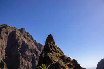 Fototapeta premium Sharp pinnacle in centre of remote tourist village Masca in the Teno mountain range, Tenerife, Canary islands, Spain, Europe. Rock formation is surrounded by steep cliffs. Gulch connceted to the sea