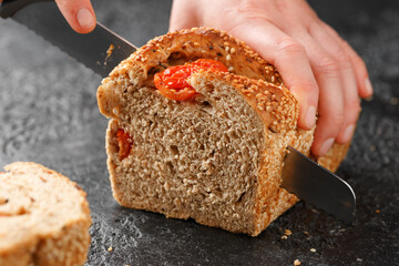 Woman slices bread with sesame seeds and sun dried tomatoes