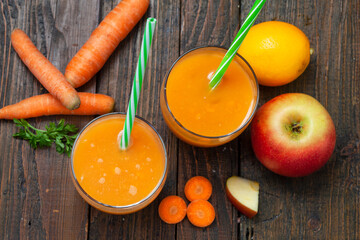 Natural organic fresh juice made of carrots and apples on wooden table. Healthy carrot, apple and lemon smoothie.