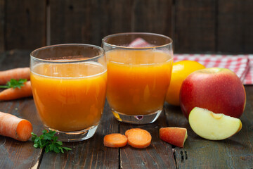 Natural organic fresh juice made of carrots and apples on wooden table. Healthy carrot, apple and lemon smoothie.