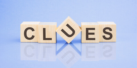clues word written on wood block for your design, blue background