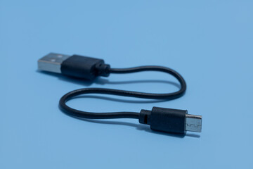 close up of Connector micro-USB, USB with cable, isolated on blue background. Black cable for data...