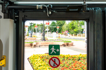 Inside a modern electric bus. View of closed doors of moving public transport. A button in the bus cabin for passengers to communicate with the driver.