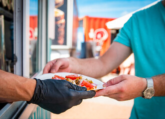 chef hands gives a pita mini pizza to man from food truck on street. street food, fast food.