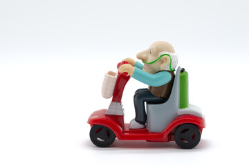 Grandfather on motorized wheelchair, toys, white background, cropped image