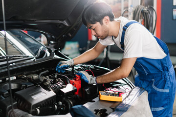 Fototapeta na wymiar Car Service Center and Automobile Maintenance, Asian Auto mechanic is diagnosing the cause of an engine problem that needs to be fixed at the garage