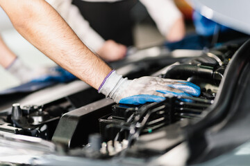 Obraz premium Close up of a technician operating and inspecting an engine while wearing gloves, Car Service and Automobile Maintenance Concept