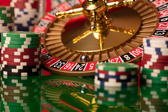 Casino. Roulette wheel and poker chips on the green shining background.