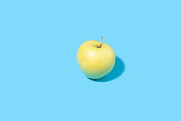 Ripe yellow apple on a blue background.