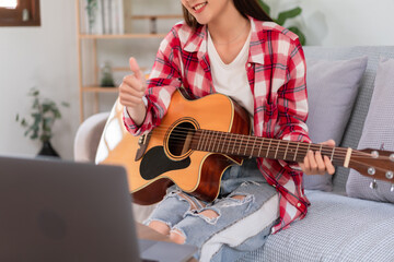 Hobby concept, Young asian woman playing acoustic guitar on live stream and doing thumbs up gesture