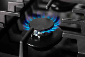 The gas burner of the black stove burns with a blue flame. Production and use of fossil fuels