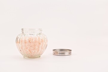 contenitore in vetro e coperchio in metallo con sale rosa dell'Himalaya su sfondo bianco