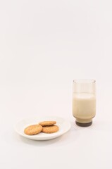 bicchiere con latte e piatto da dessert con biscotti, concetto di spuntino e colazione