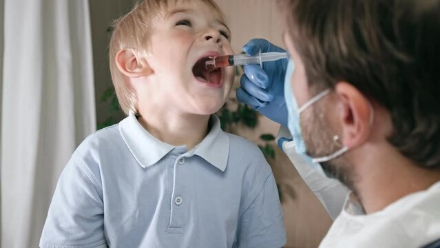 Kid getting polio drops. Doctor making to Child Oral Vaccination against infection. Little Blonde Hair Boy at Hospital. Children health care and disease prevention. Via of Polio Vaccine. Immunization.