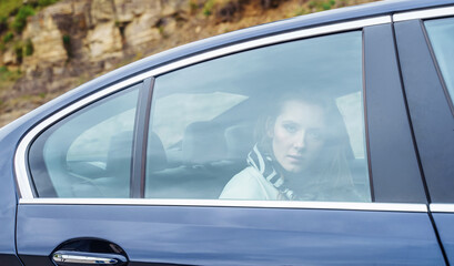 Beautiful woman on the back seat of a car looking out of the window.