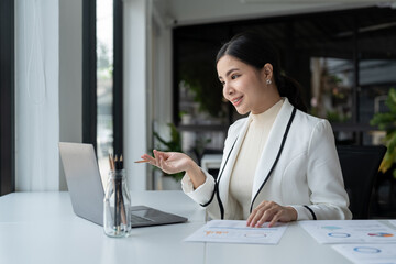 Asian woman holding webinar or giving online business consultation to client. Female entrepreneur or corporate company manager having remote online telework meeting via video call on laptop computer