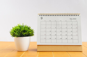 September 2022 Desktop calendar for planners and reminders on a wooden table with plants on a white background.