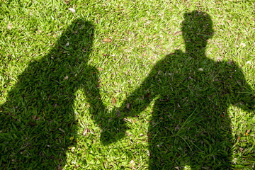 Two shadow man and woman couple on green grass, Two shadows of people, Couple shadow holding hand on green grass, Pair of lovers shadows, Love concept.
