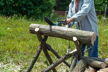 Cord Chainsaw. Close-up of woodcutter sawing chain saw in motion, sawdust fly to sides. Chainsaw in motion. Hard wood working in forest. Sawdust fly around. Firewood processing.