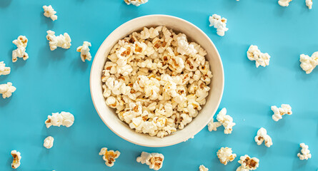 Plate with popcorn on a blue background, flat lay.