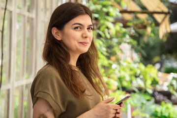 Attractive woman in a smartphone in a greenhouse for plants.