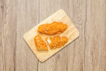 Sliced fried chicken on wooden butcher table