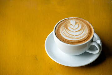 Close up of Hot coffee latte art with pattern on top, warm feeling coffee on table, vintage cup with copy space