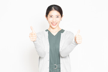 白背景の前で、良いねのポーズをする女性
