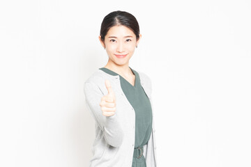 白背景の前で、良いねのポーズをする女性