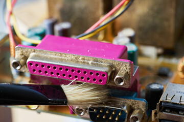 Brush cleaning an old computer board from dust and dirt. Close-up.
