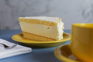 A piece of a cheesecake on a yellow plate. Close-up with selective focus.