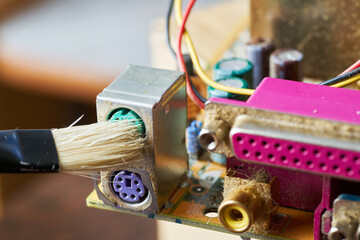 Brush cleaning an old computer board from dust and dirt. Close-up.